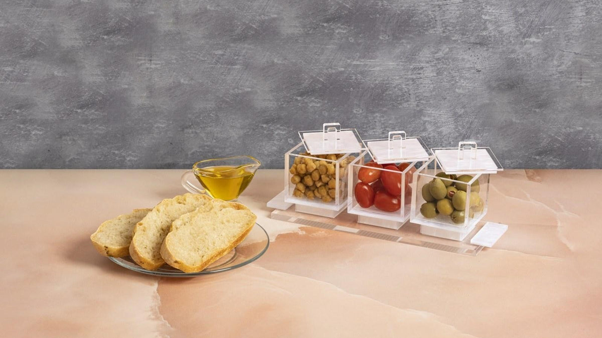 Clear serving dishes with snacks beside bread and a dip bowl