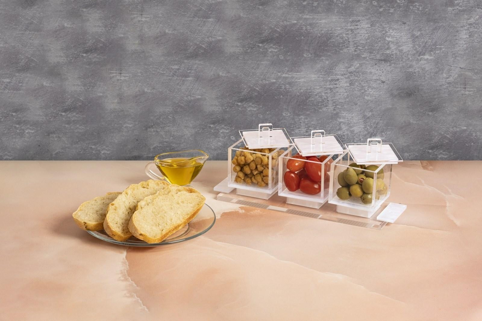 Clear serving dishes with snacks beside bread and a dip bowl