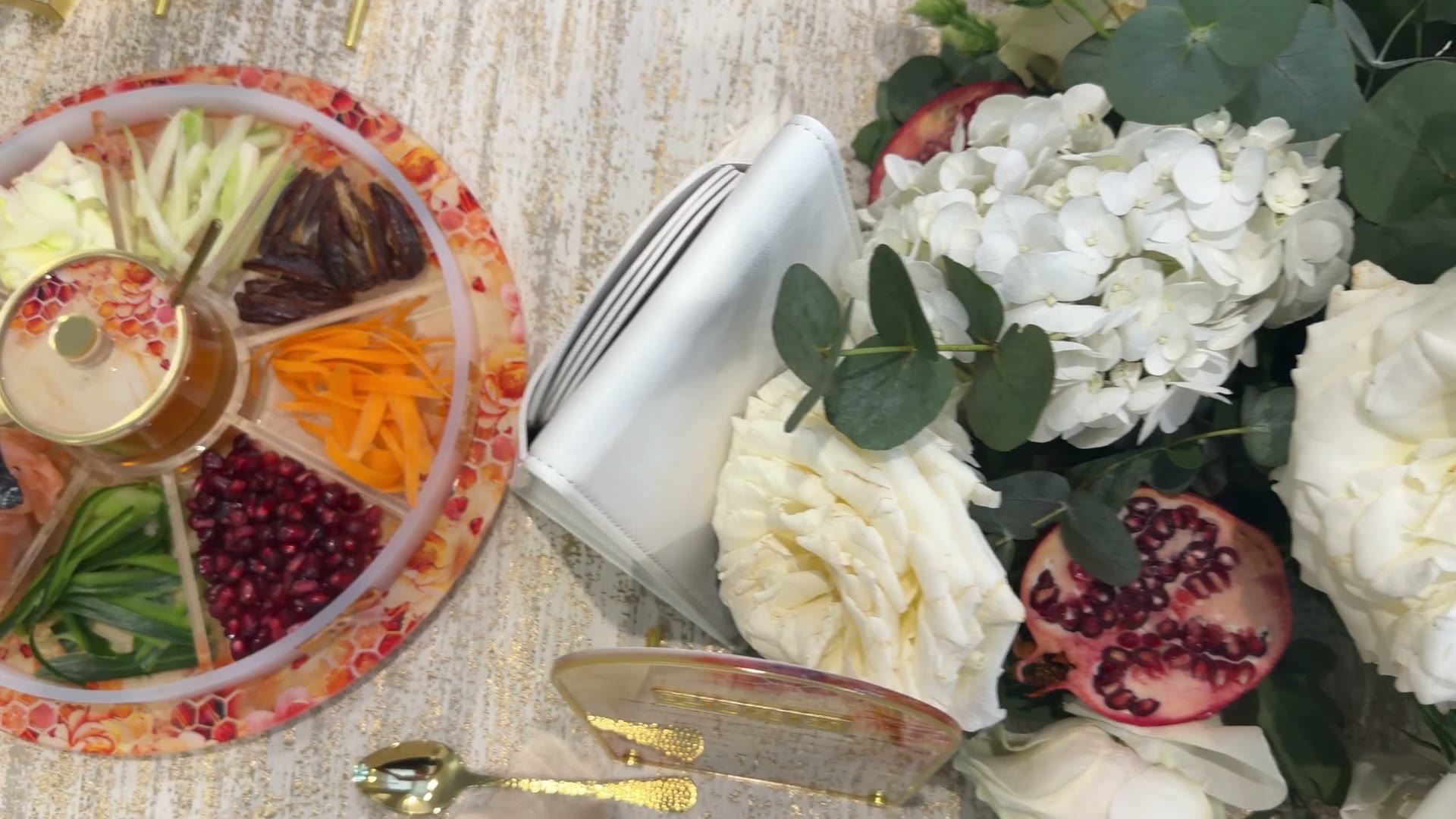 Rosh Hashanah table set with white florals, pomegranate and lucite simanim pieces